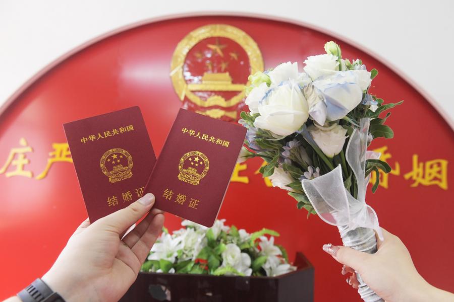 10 августа 2024 года, после бракосочетания пара молодоженов сфотографировала на память свидетельства о браке в городе Синьлэ пров. Хэбэй на севере Китая. /Фото: Синьхуа/